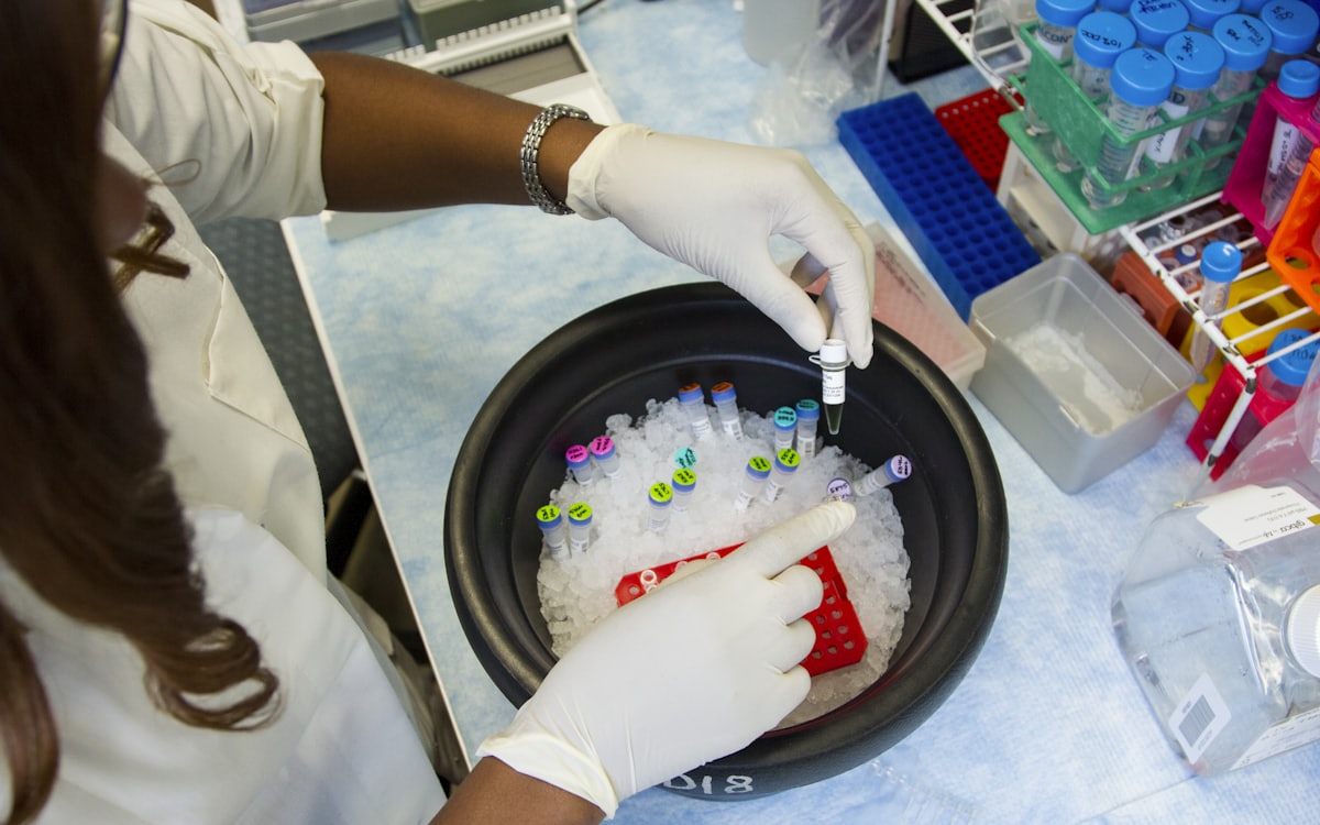 A researcher in gloves handling labelled sample vials on ice in a laboratory
